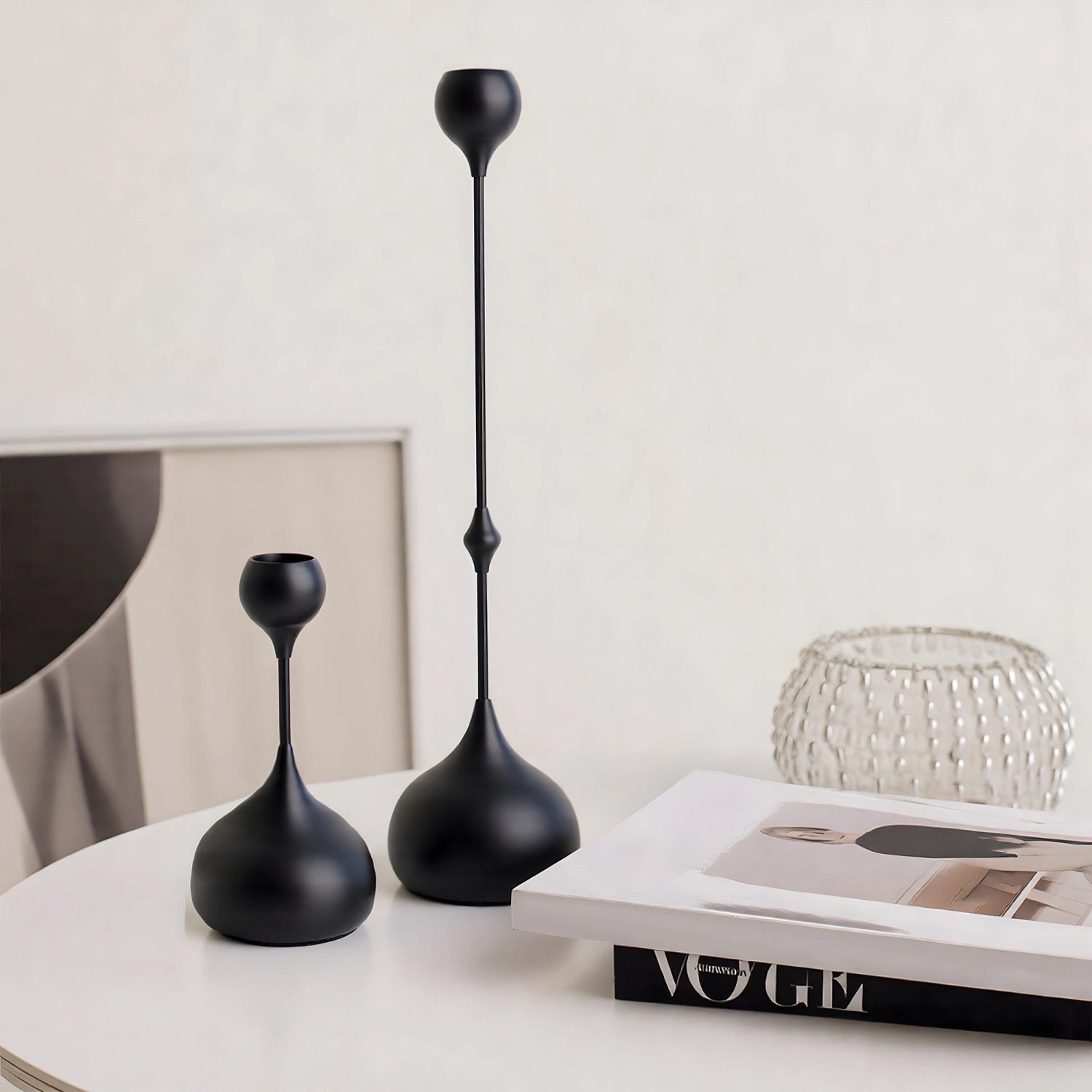 Two black candle holders on a table with a magazine in the background