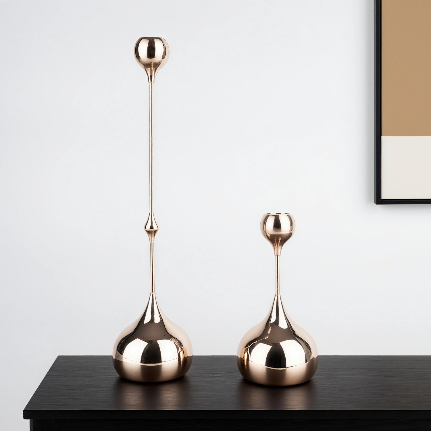 Two gold decorative vases on a black surface with a white wall background