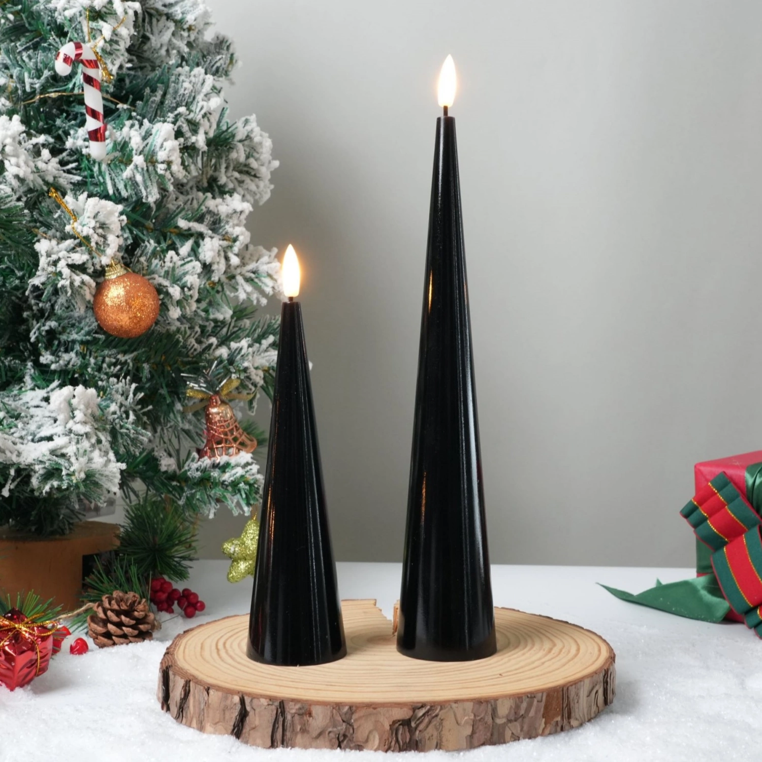 Two black candles on a wooden stand with a Christmas tree and presents in the background.#color_shiny-black