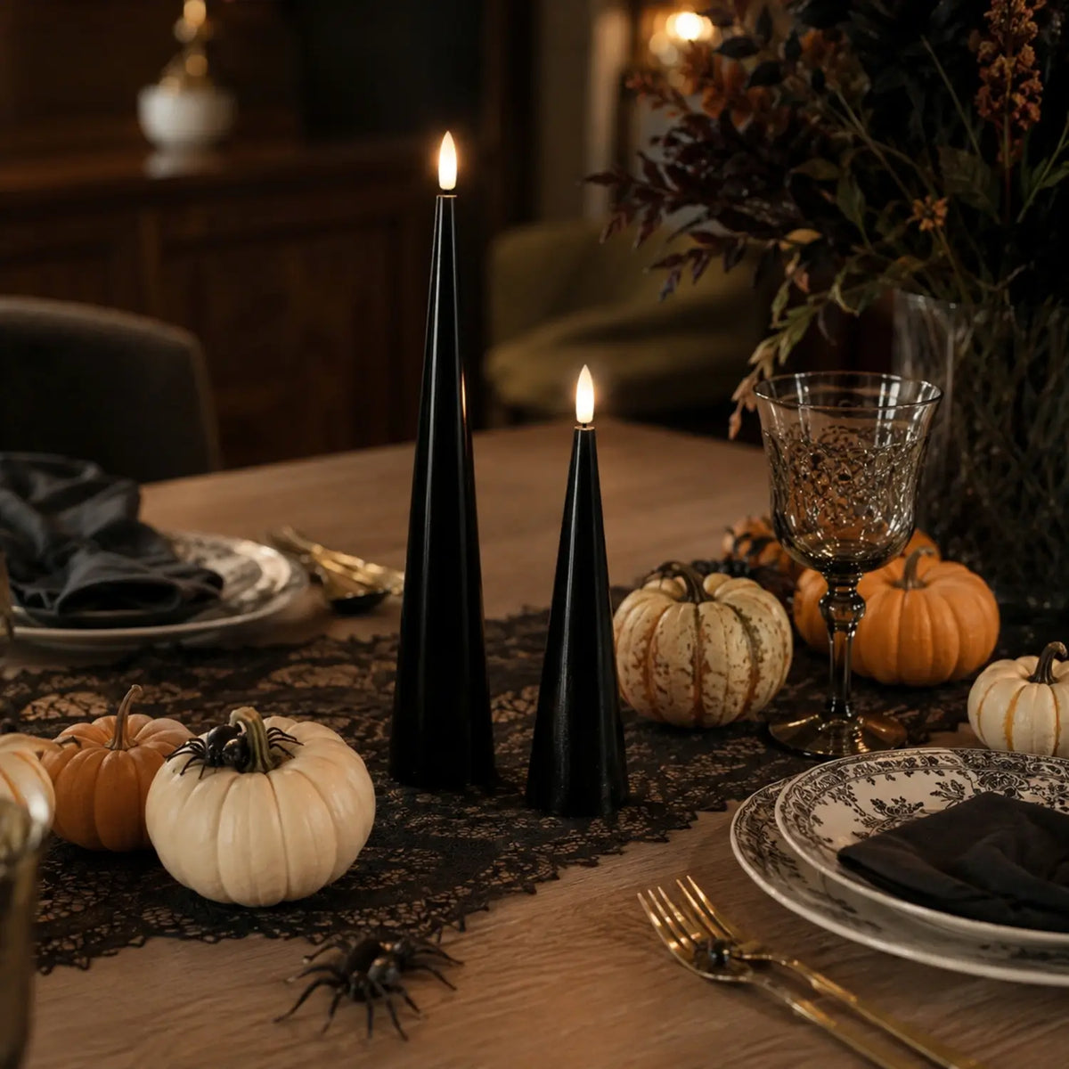 Black cone-shaped candles with lit flames on a table with Halloween decorations.#color_shiny-black