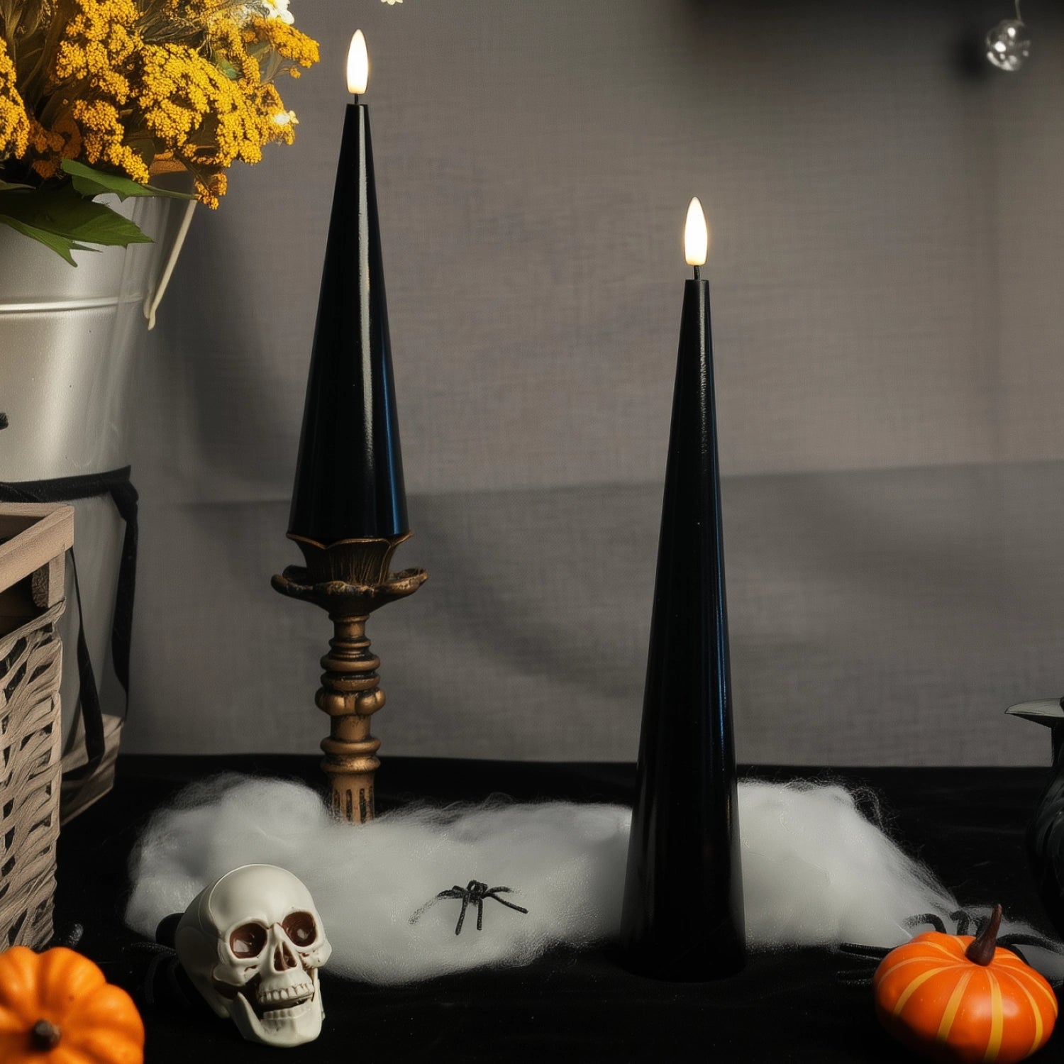 Halloween-themed setup with black candles, skull, pumpkins, and spider on a dark surface.#color_shiny-black