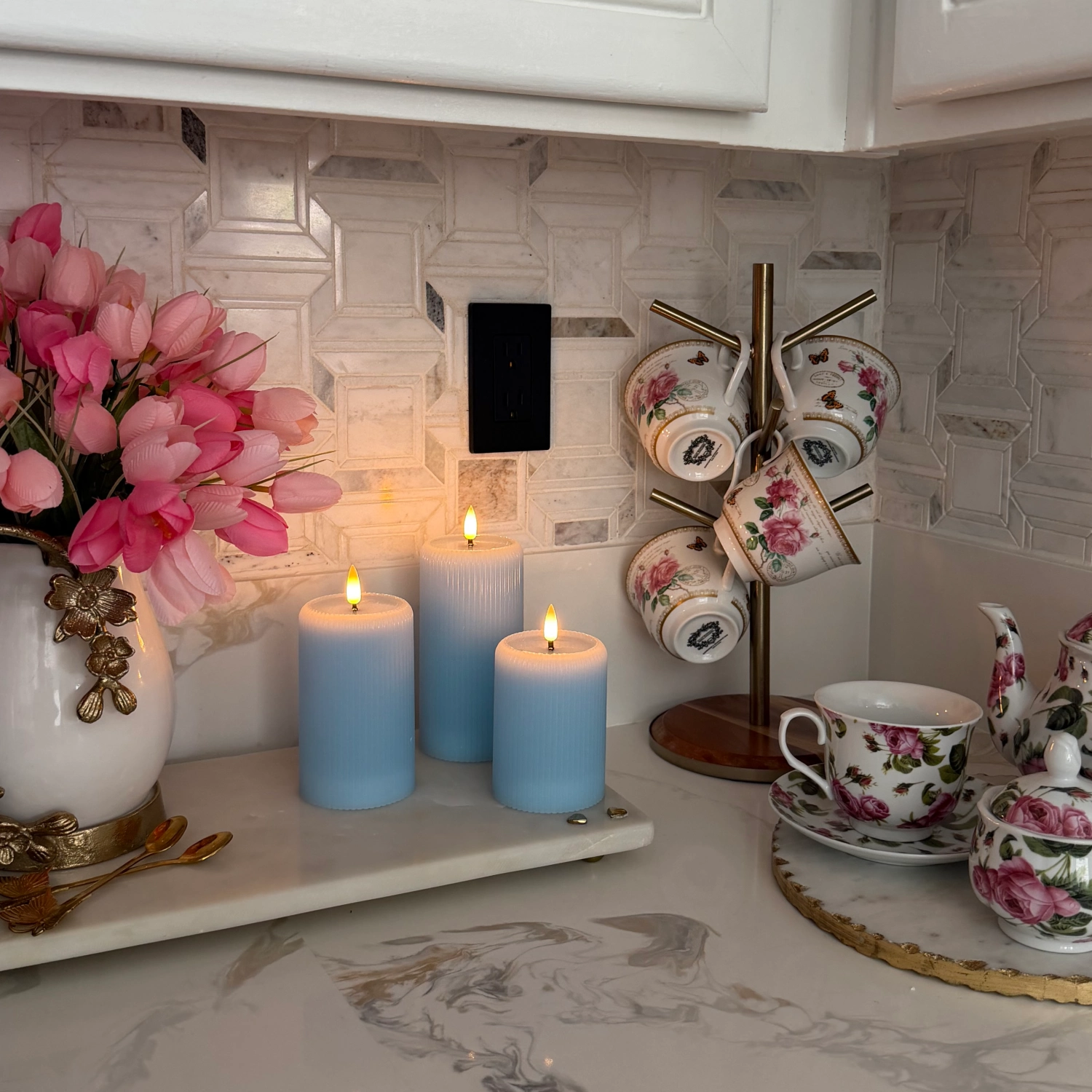 Decorative shelf with candles, flowers, and teacups in a kitchen setting