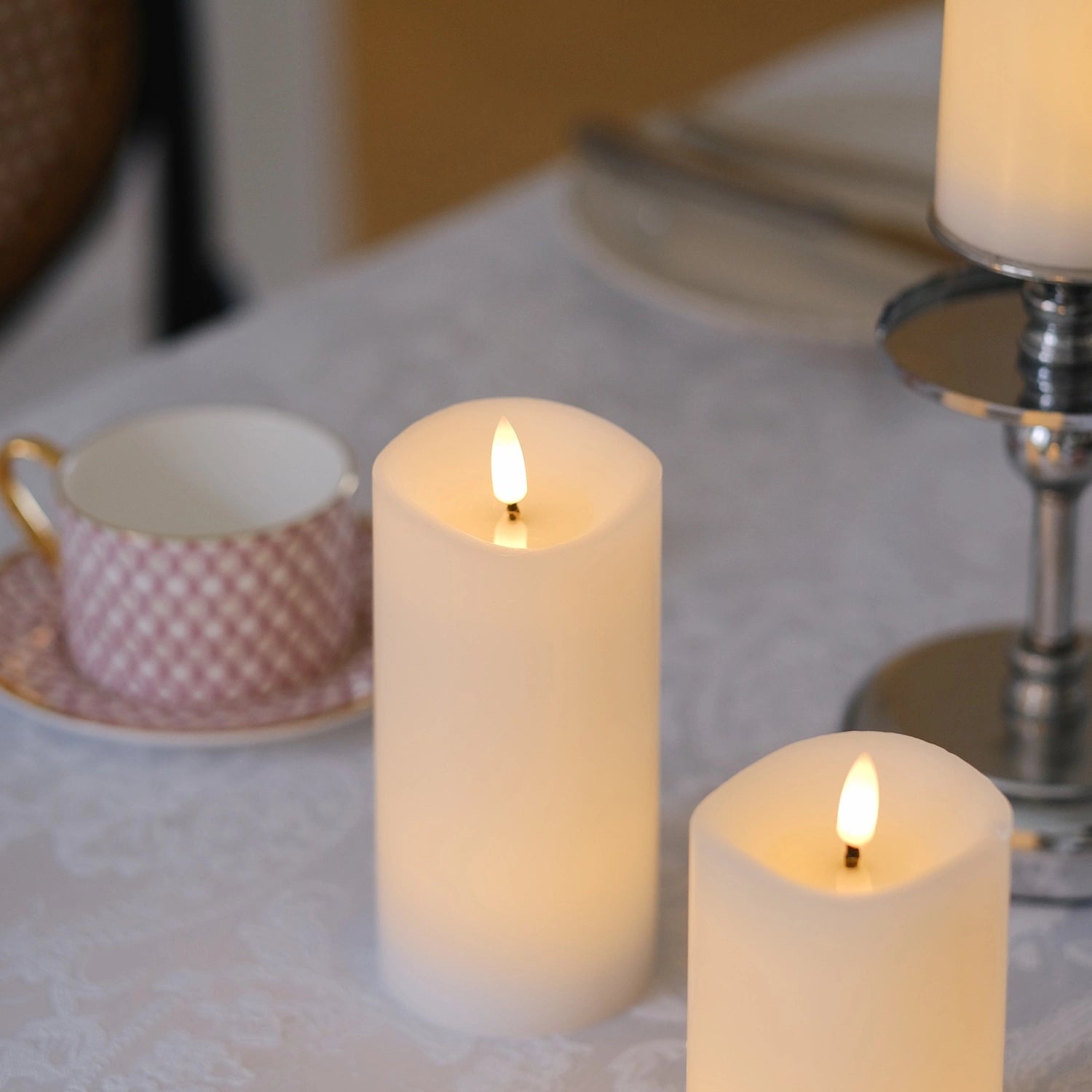 Decorative table setting with candles and greenery on a white tablecloth.#color_white