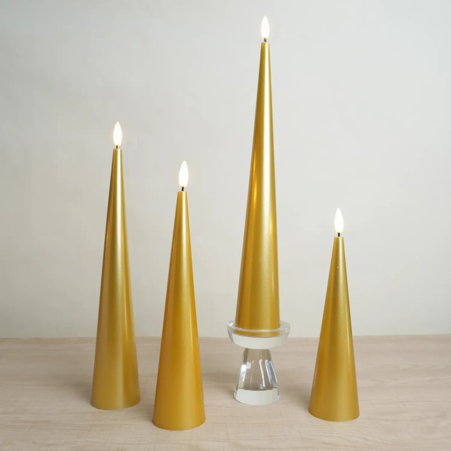 Set of four gold cone-shaped candles on a wooden surface with a plain background