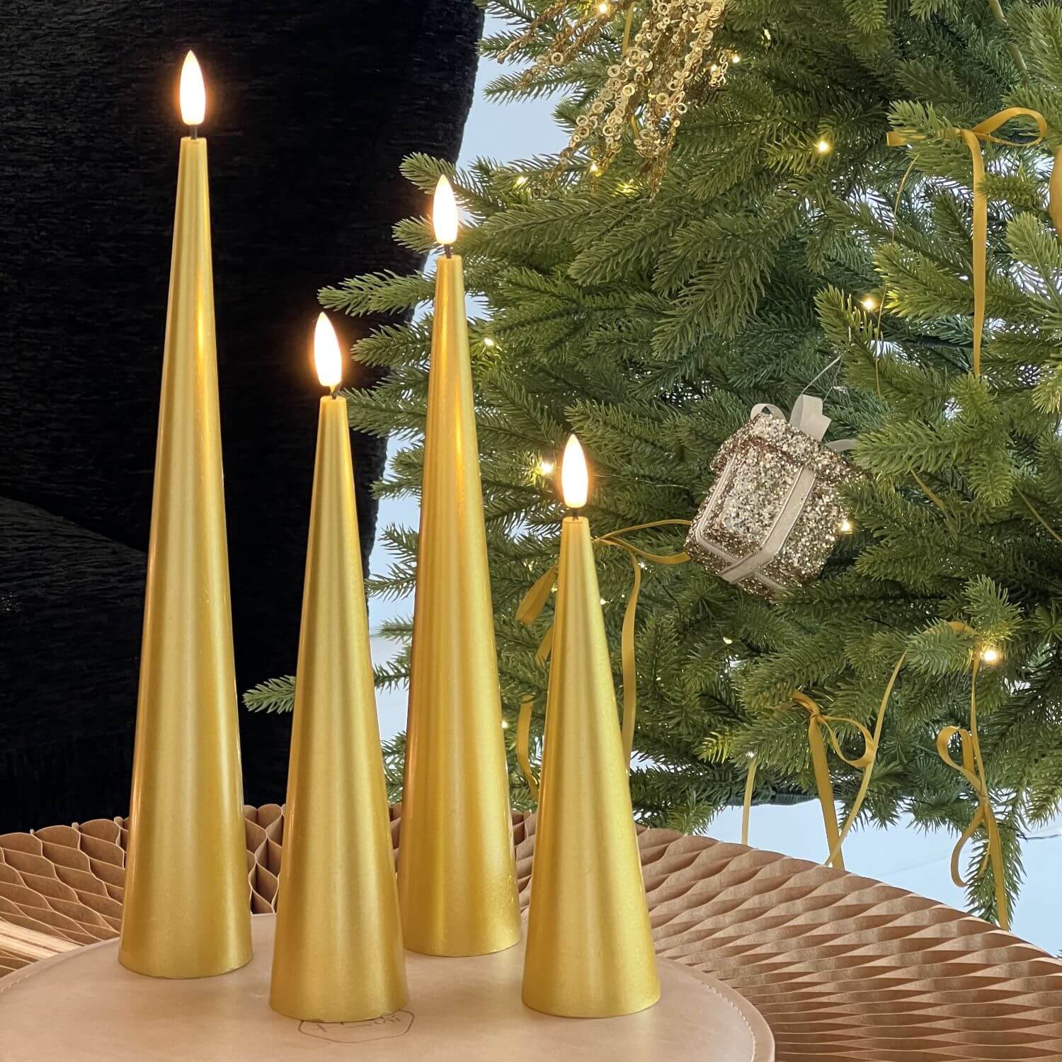 Decorative setup with gold candles, flowers, and greenery on a marble surface.#color_lacquered-gold