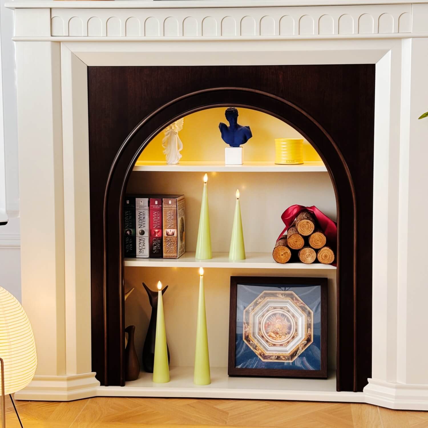 Decorative shelf inside a fireplace with books, candles, and decorative items.#color_shiny-green