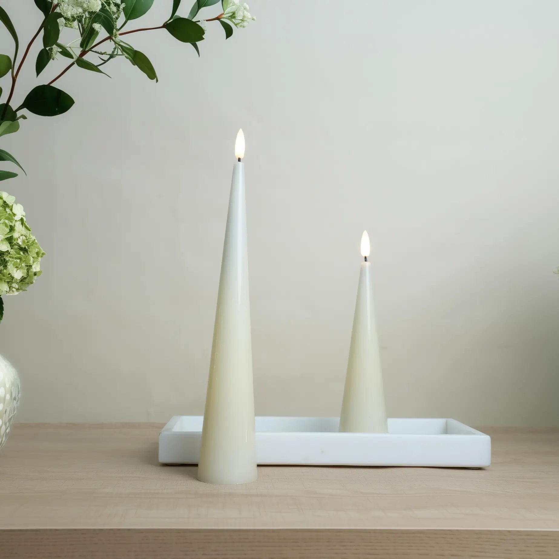 Two white candles on a white tray with a neutral background