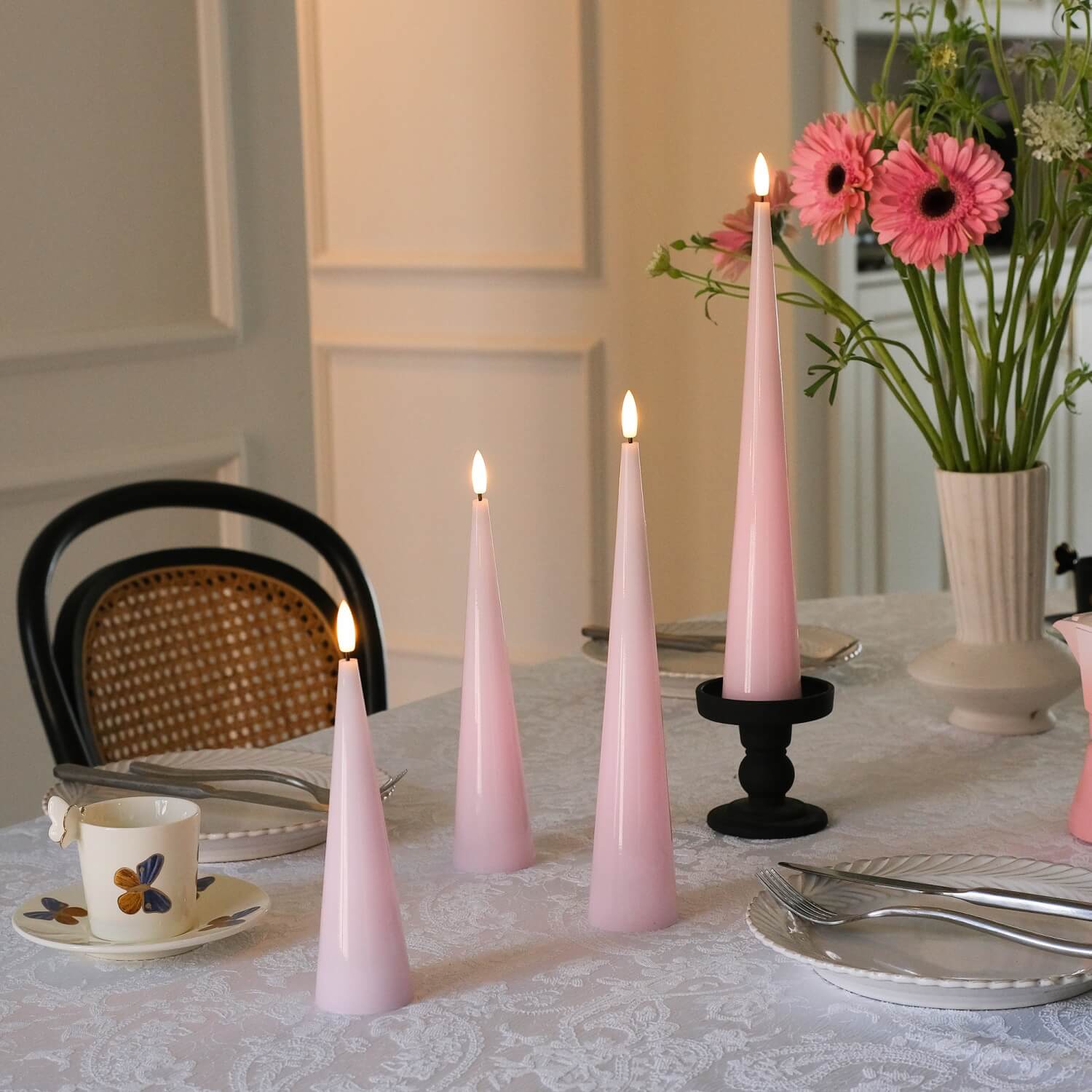 Pink taper candles on a table with floral arrangement and cutlery#color_shiny-pink
