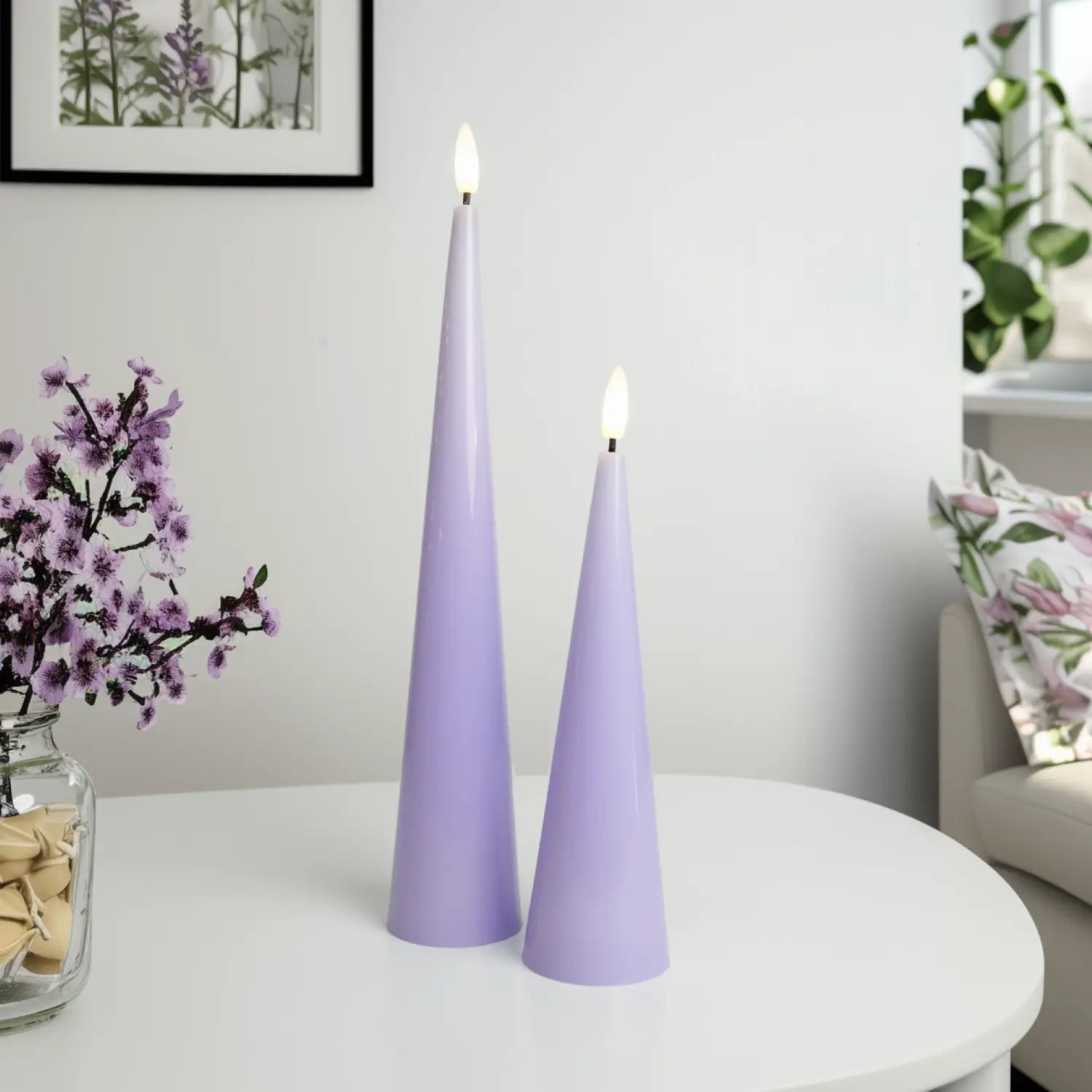 Two purple cone-shaped candles on a white surface with a decorative background.#color_shiny-purple