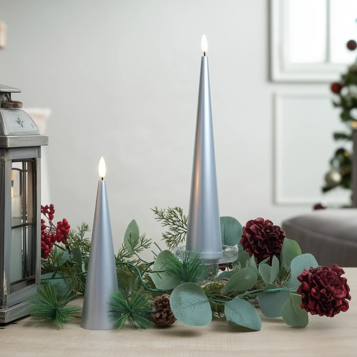 Decorative setup with silver candles, greenery, and red flowers on a table.#color_lacquered-silver