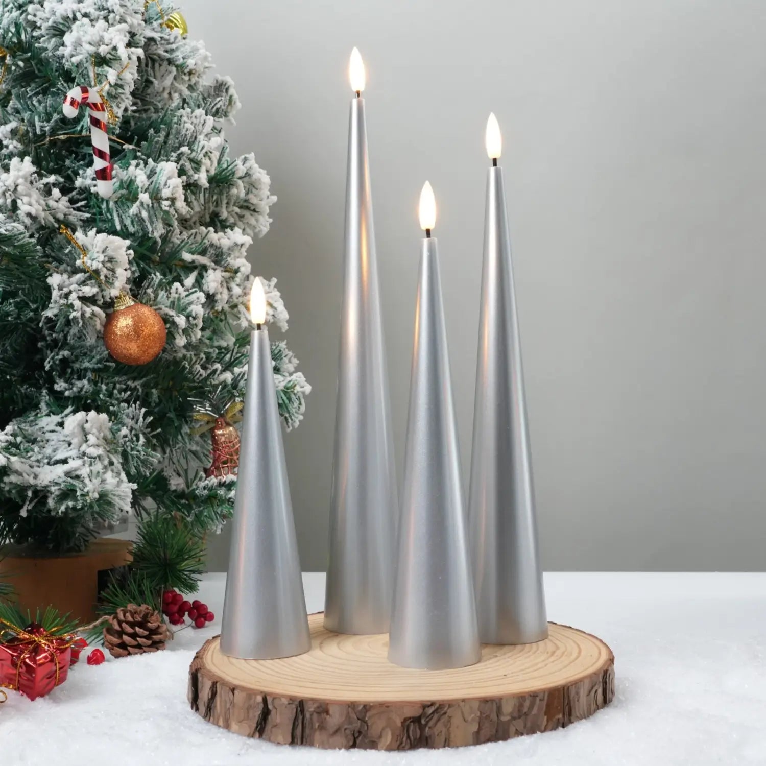 Decorative candles on a wooden base with a Christmas tree in the background#color_lacquered-silver