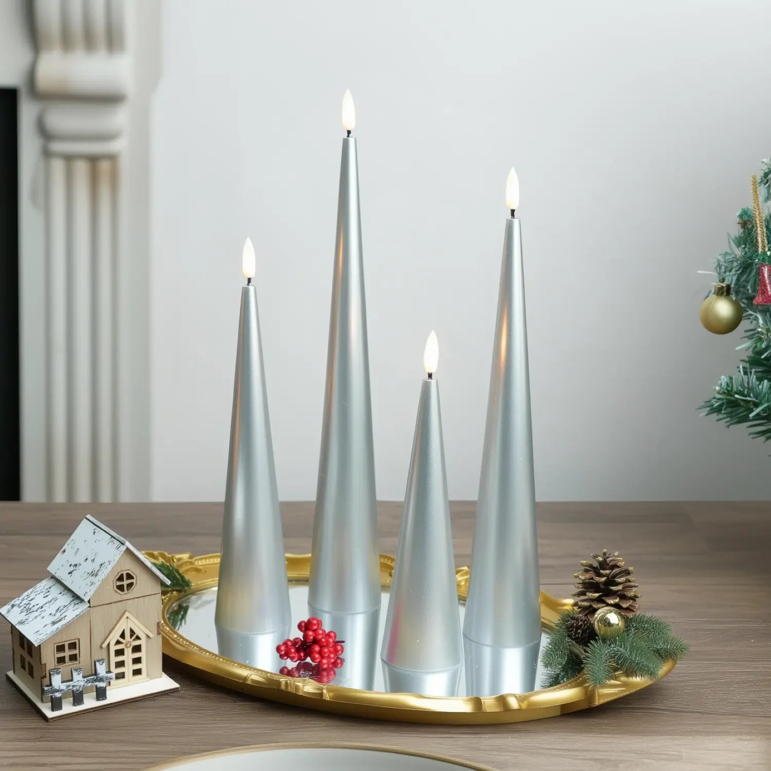 Set of four gray cone-shaped candles on a table with a fireplace and Christmas decorations in the background.#color_lacquered-silver