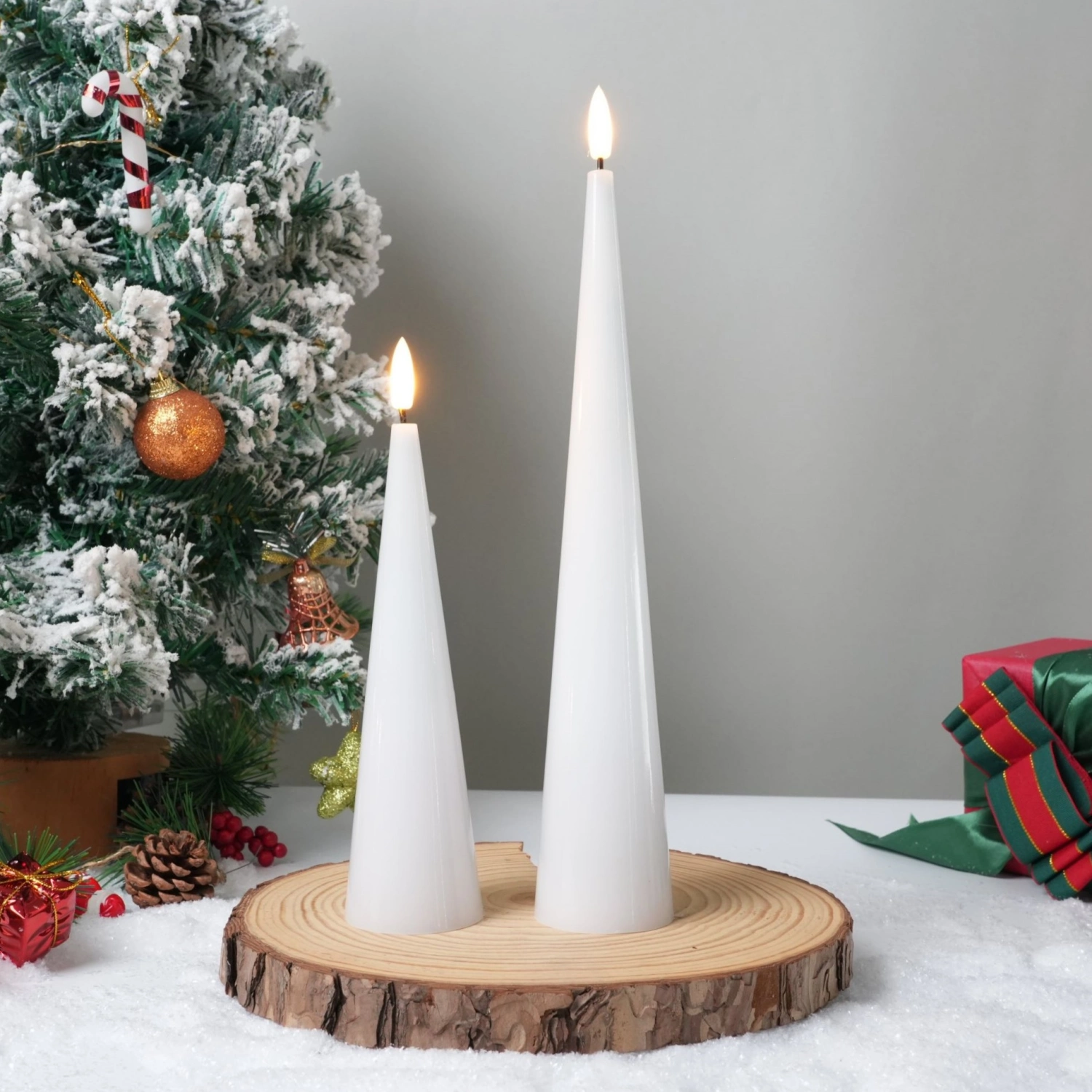 Two white candles on a wooden stand with a Christmas tree and gift in the background.#color_shiny-white