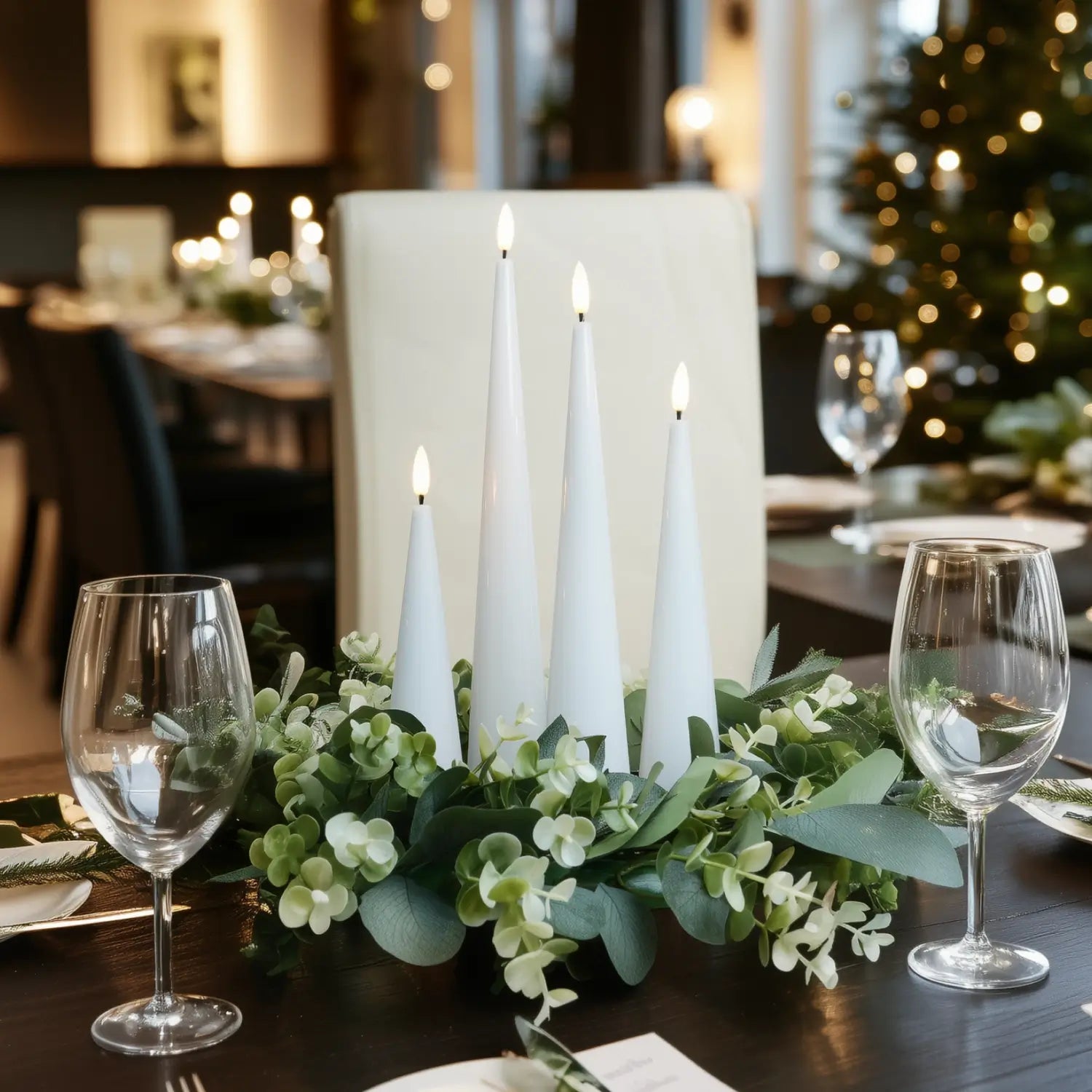 Decorative table setting with candles and greenery in a festive indoor setting.#color_shiny-white