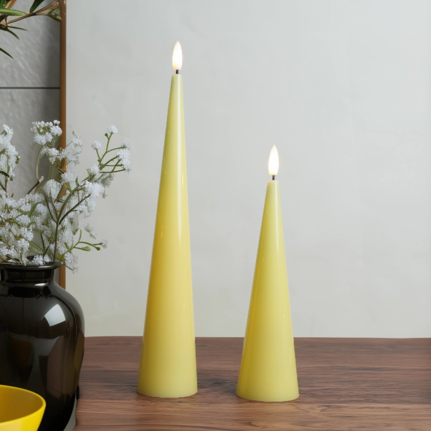 Two yellow cone-shaped candles on a wooden surface with a neutral background#color_shiny-yellow