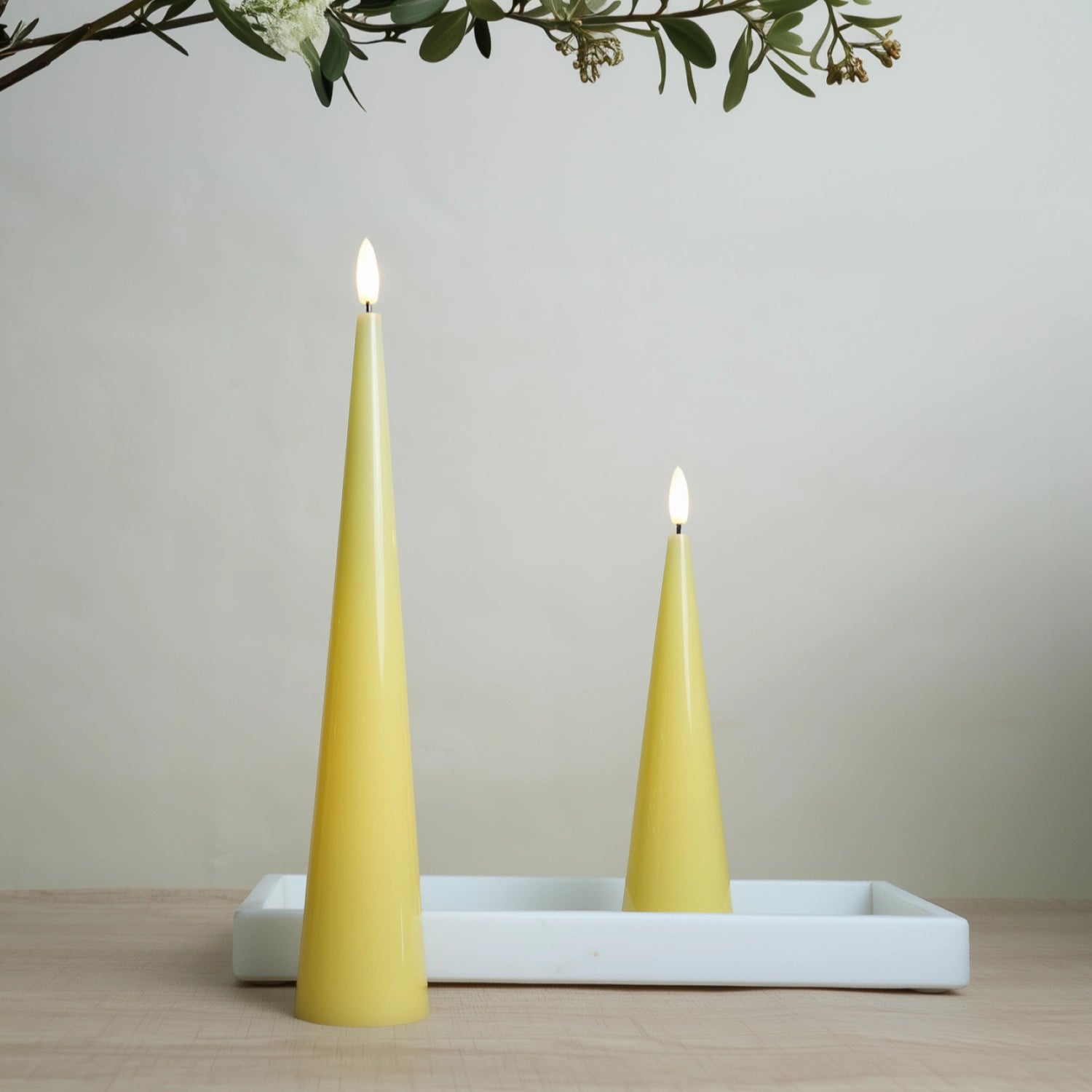 Two yellow candles on a white tray with a neutral background#color_shiny-yellow