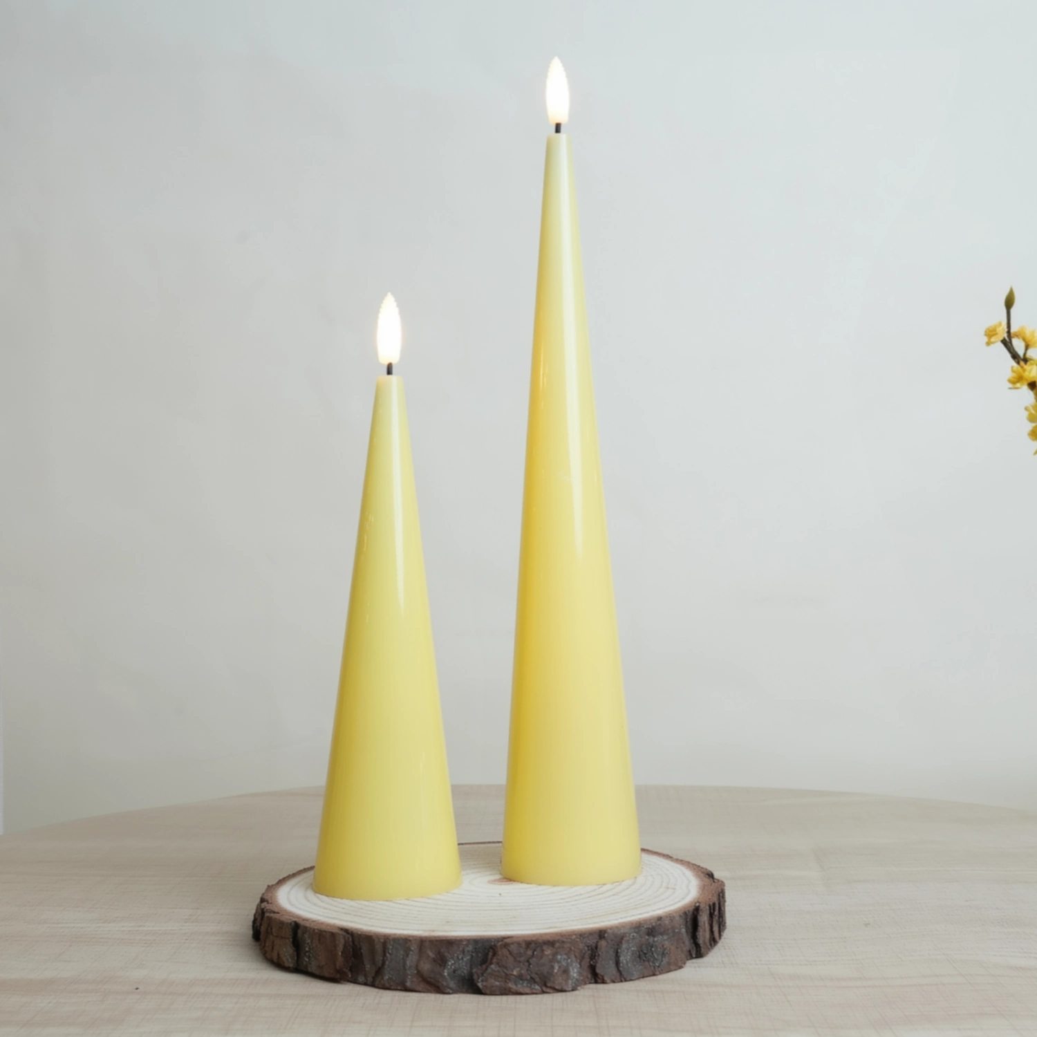 Two yellow taper candles on a wooden stand against a plain background#color_shiny-yellow