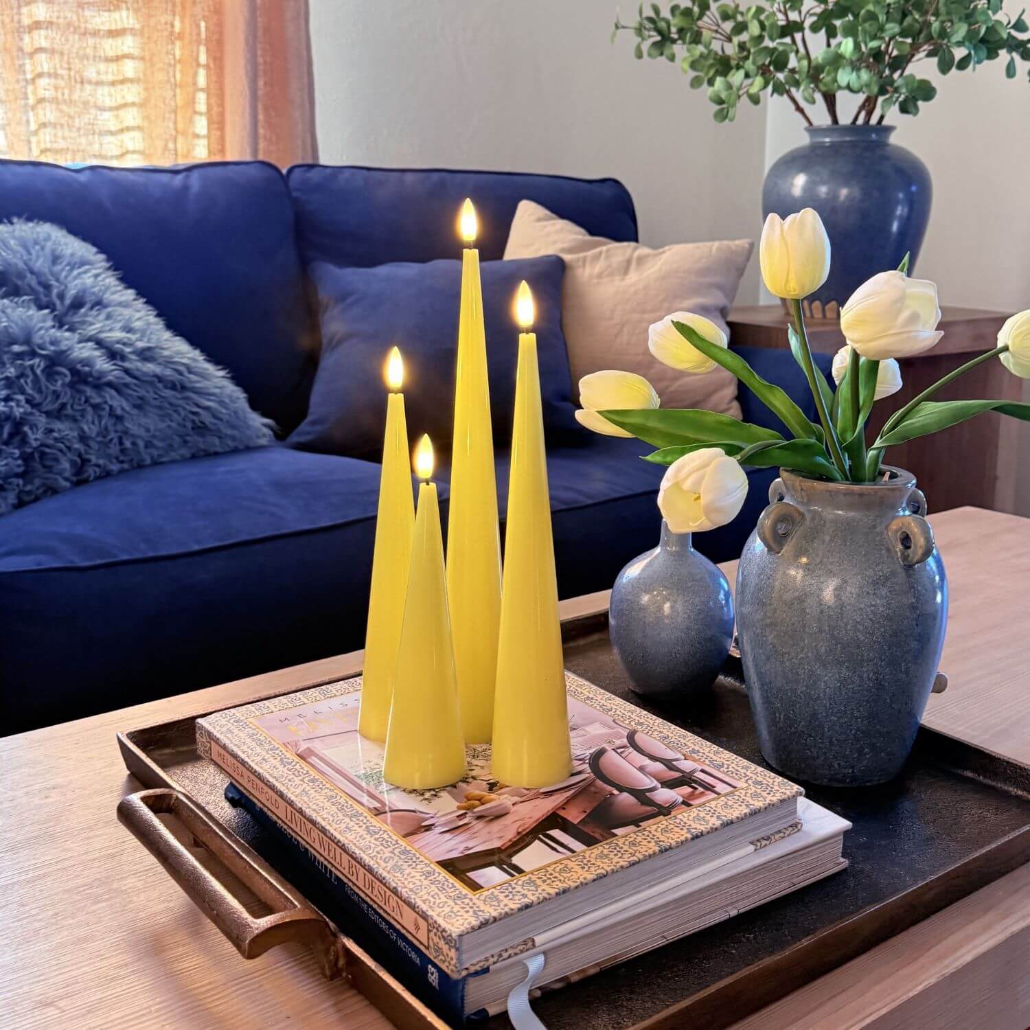 Set of four yellow taper candles on a wooden surface with a neutral background#color_shiny-yellow