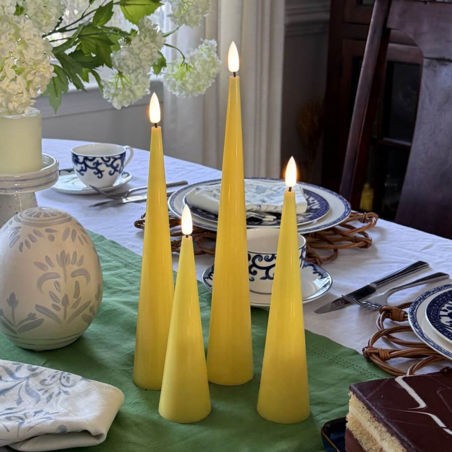 Set of four yellow taper candles on a wooden surface with a neutral background#color_shiny-yellow