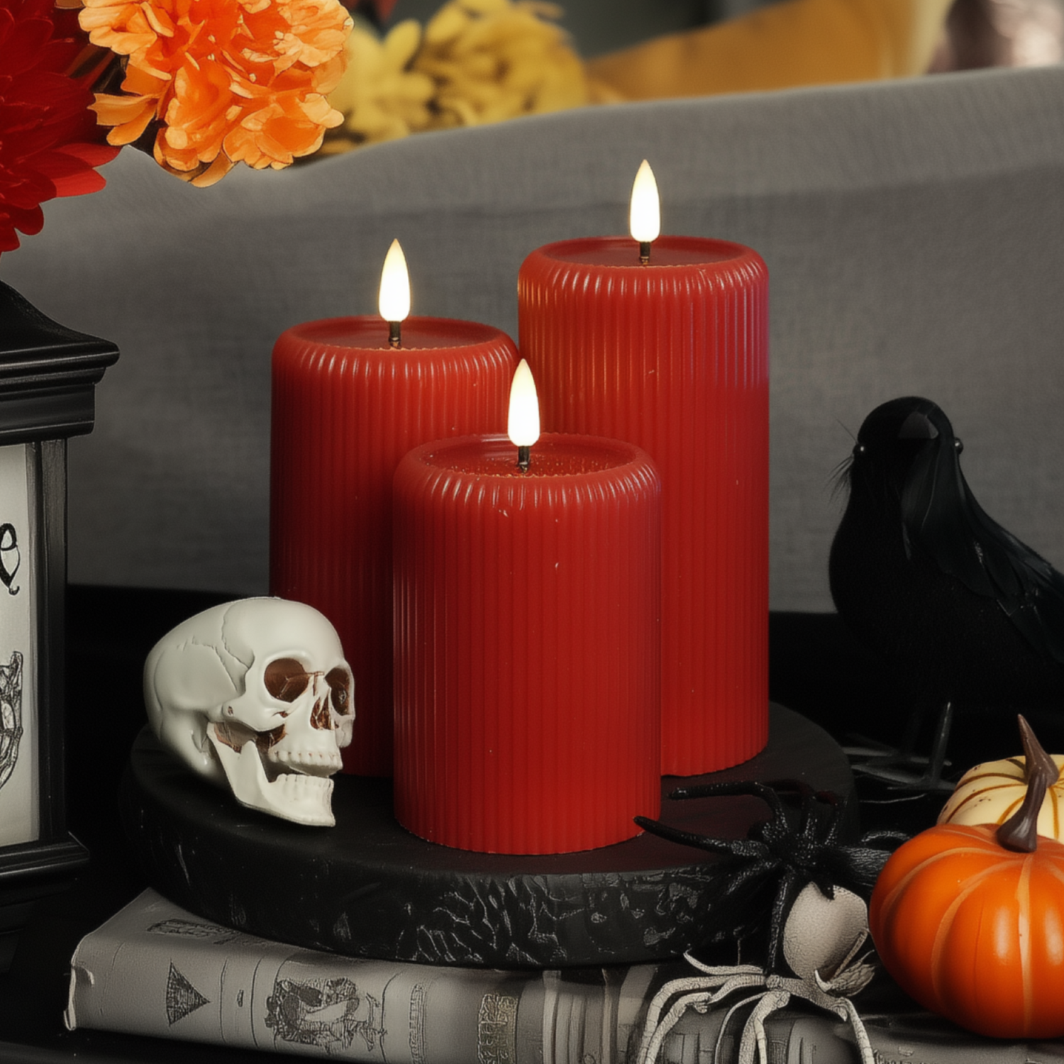 Halloween-themed arrangement with red candles, skull, pumpkins, and spider on a table.