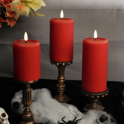 Three red candles on decorative stands with Halloween-themed decorations including a skull and spider.
