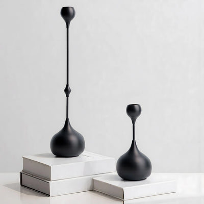 Two black decorative vases on white surfaces with a light gray background