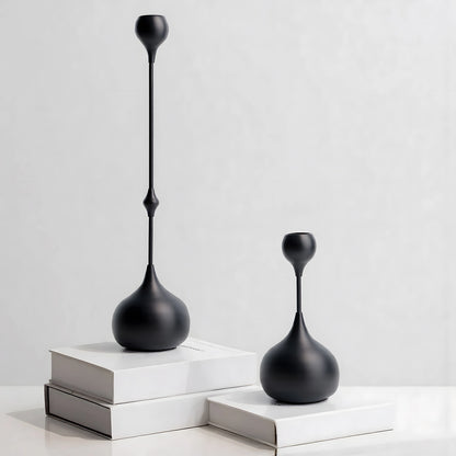 Two black decorative vases on white surfaces with a light gray background