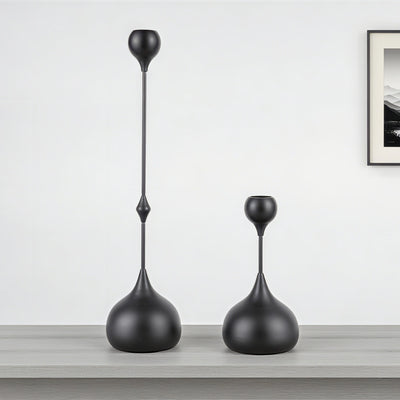 Two black decorative vases on a wooden surface with a white wall background