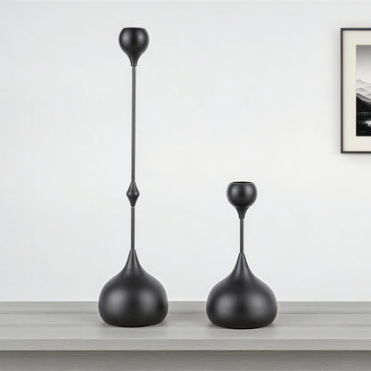 Two black decorative vases on a wooden surface with a white wall background