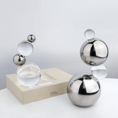 Decorative metal sculptures on a white surface with a light gray background