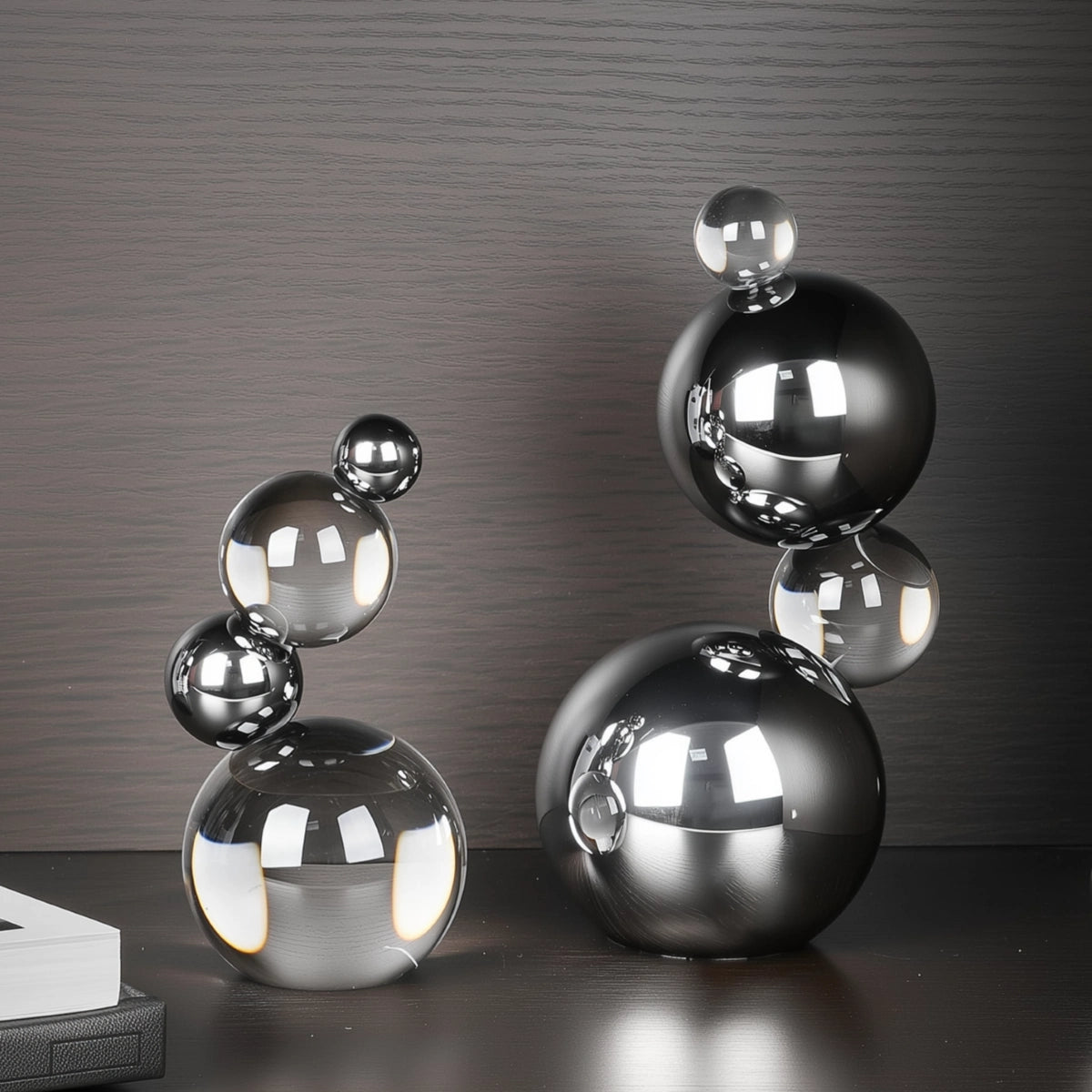 Decorative sculpture of stacked metallic spheres on a reflective surface with a dark background