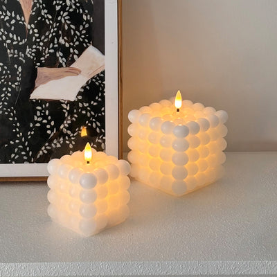 Two bubble-textured candles on a surface with a blurred background