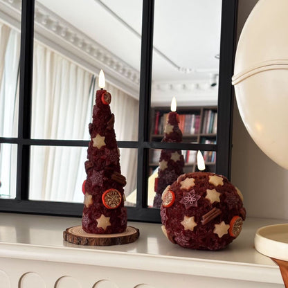 Decorative candles on a wooden base with a Christmas tree in the background