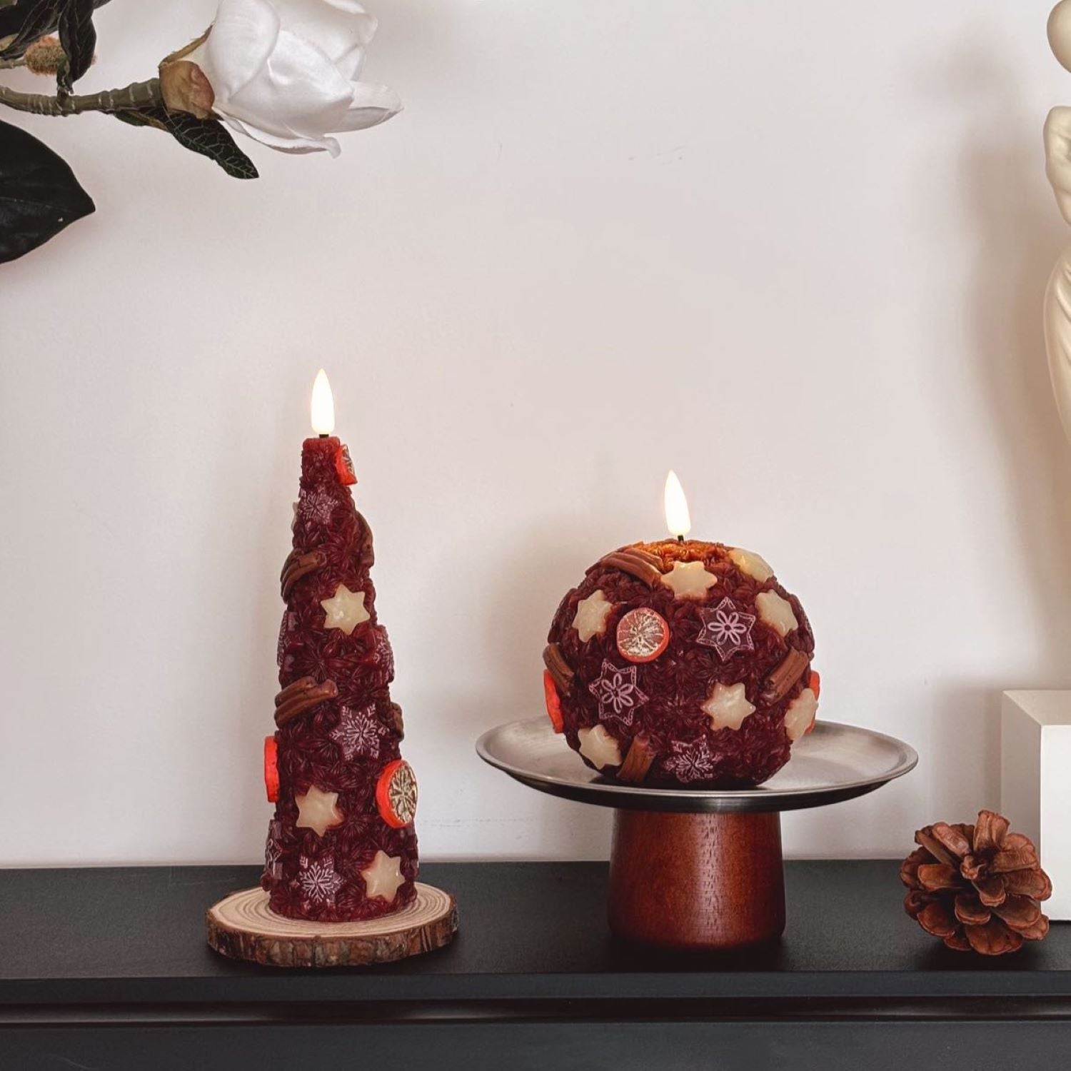 Decorative candles on a wooden base with a Christmas tree in the background