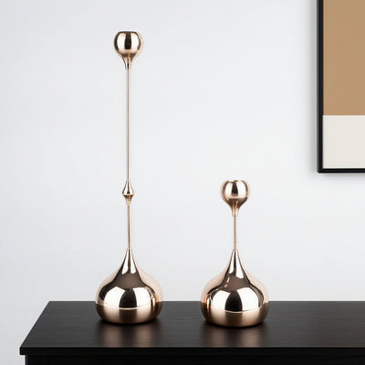 Two gold decorative vases on a black surface with a white wall background