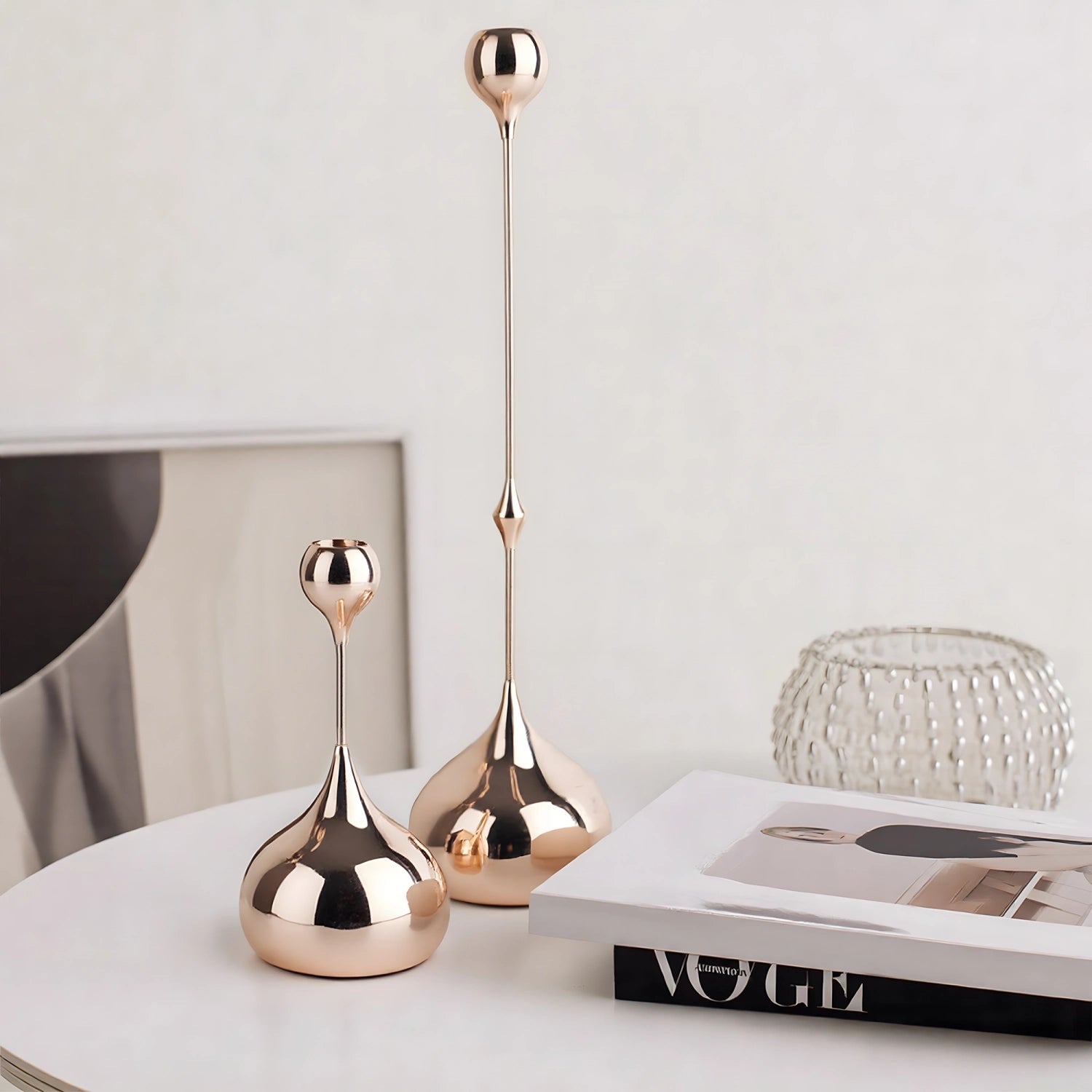 Two rose gold decorative vases on a surface with a magazine in the background.