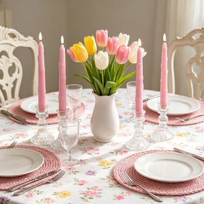 Easter table setting with pink and white tulips, candles, and floral tablecloth.