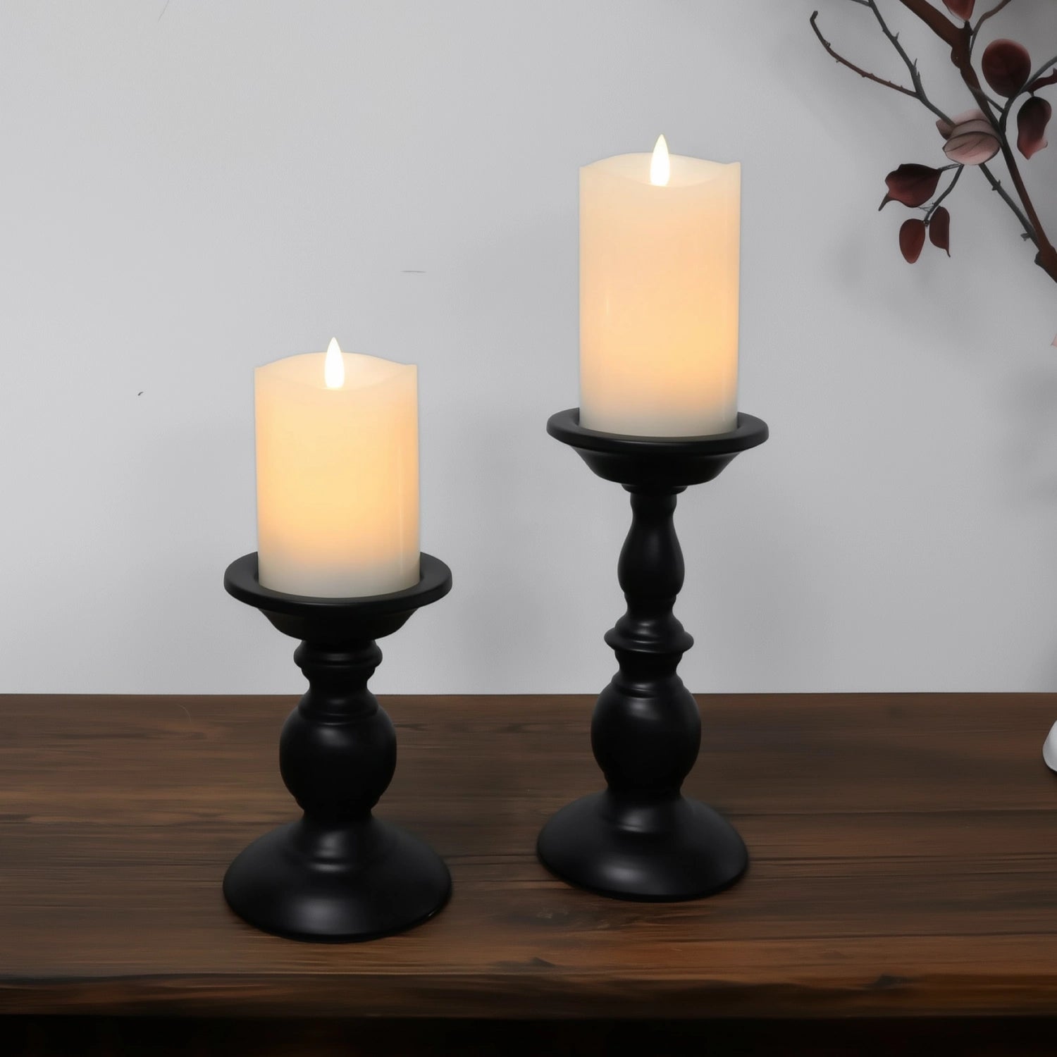 Two black candle holders with lit candles on a wooden surface.