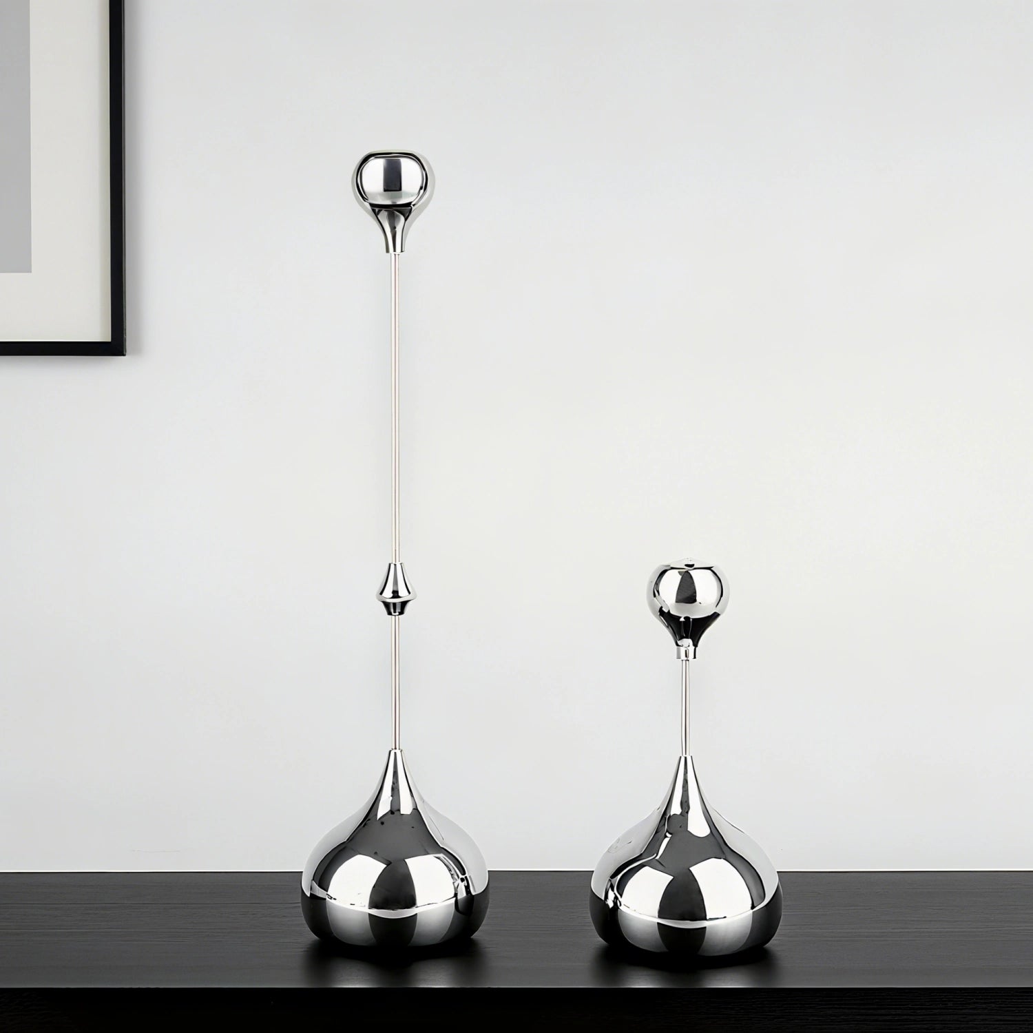 Two silver decorative vases on a dark surface with a light gray background