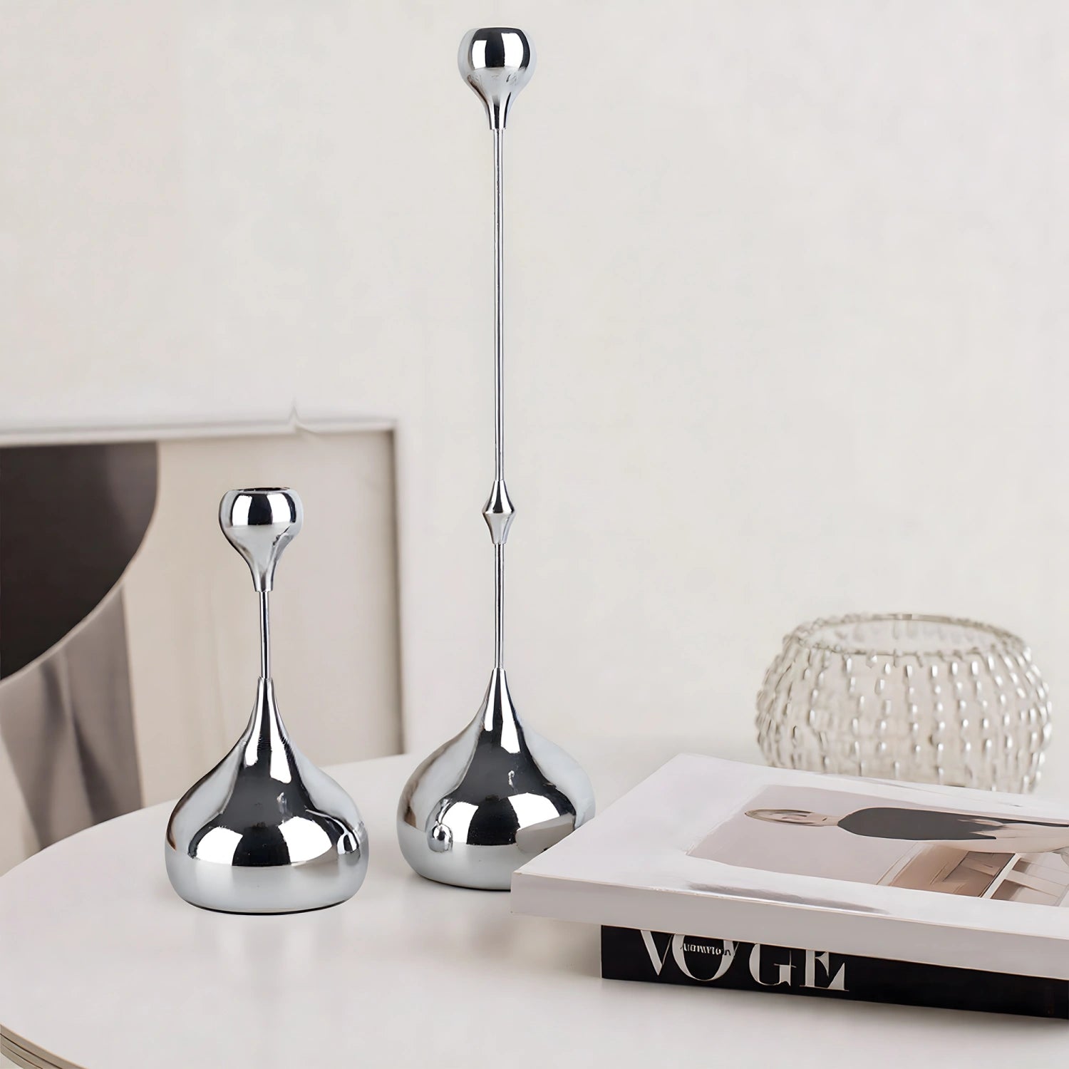 Two silver decorative vases on a surface with a magazine underneath.