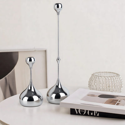 Two silver decorative vases on a surface with a magazine underneath.