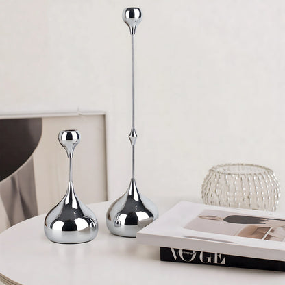 Two silver decorative vases on a surface with a magazine underneath.