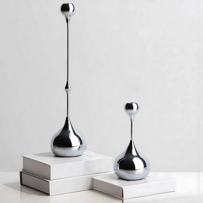 Two silver decorative vases on white surfaces with a light gray background