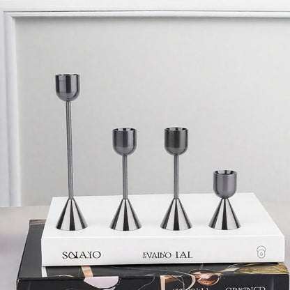 Set of four metallic candle holders on a white book with a gray background