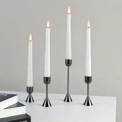 Set of four candlesticks with lit candles on a gray background