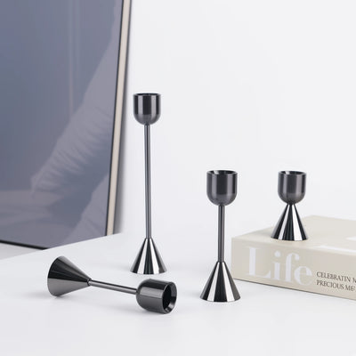 Set of black metal candle holders on a white surface with a blurred background