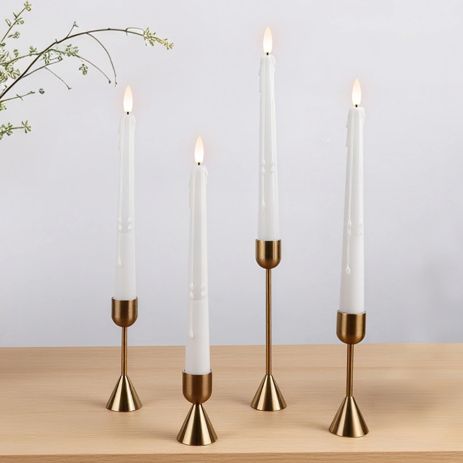 Gold candle holders with white candles on a wooden surface and light gray background