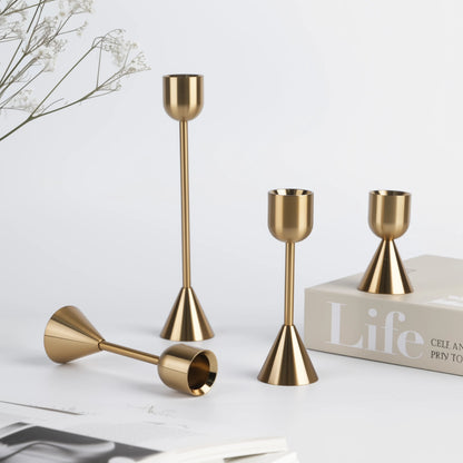 Set of gold candle holders on a white surface with a book titled 'Life' in the background.