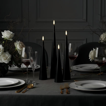 Black candles on a wooden base with a Christmas tree in the background