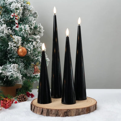 Black candles on a wooden base with a Christmas tree in the background